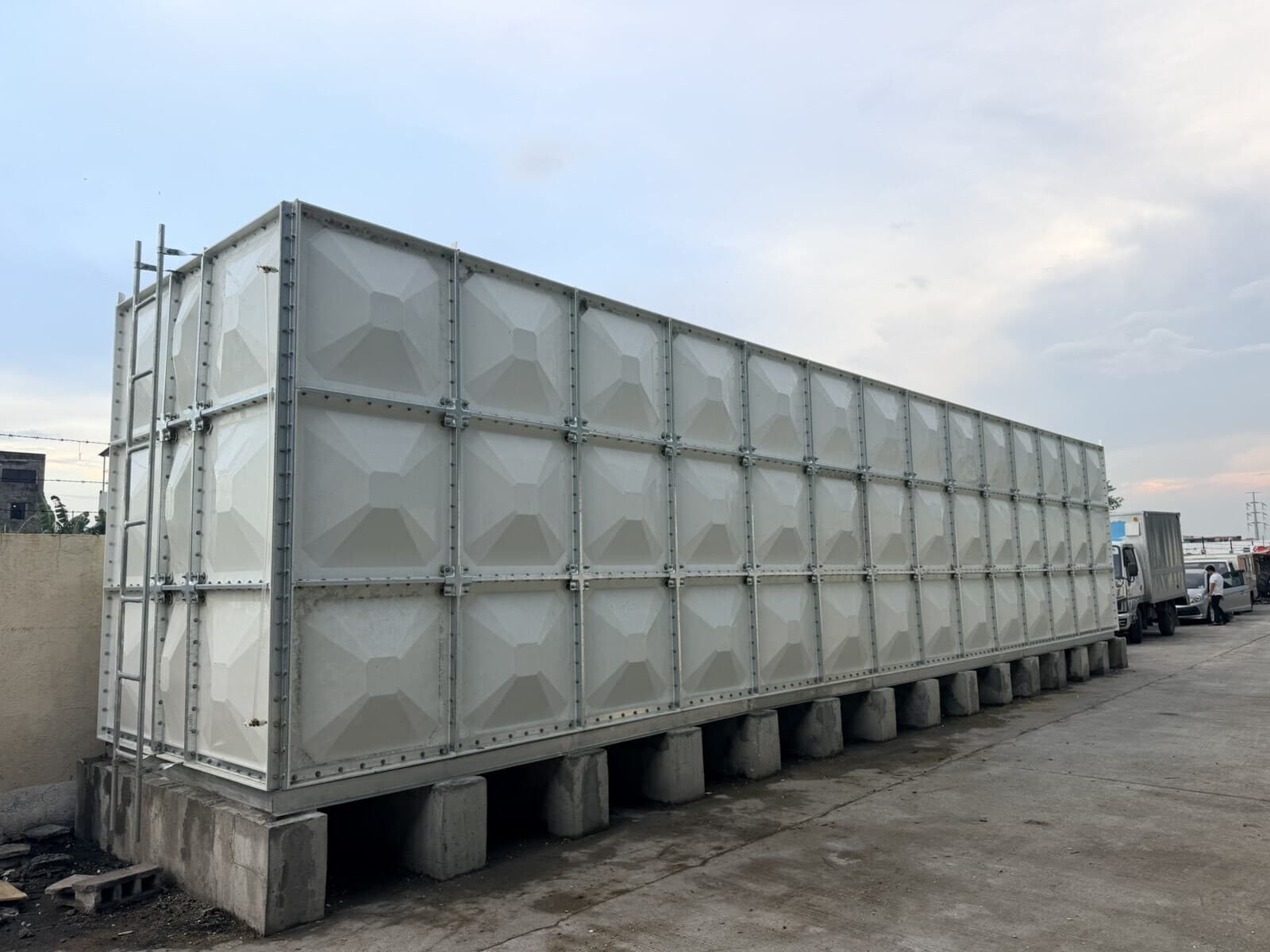 Completed 105,000-liter GRP modular water tank on reinforced concrete plinth beams at a commercial laundry in Taguig
